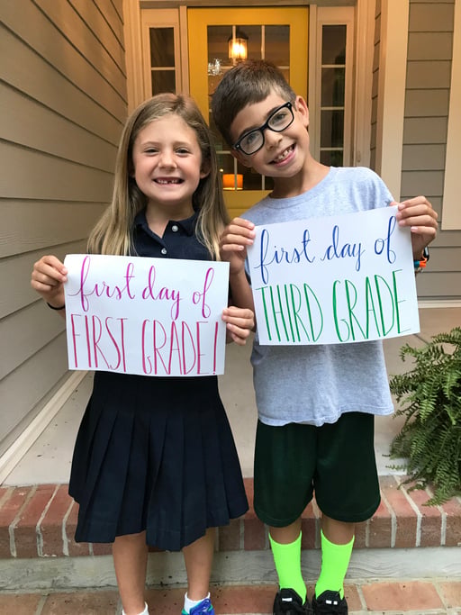 Brother and sister holding thier back to school cards
