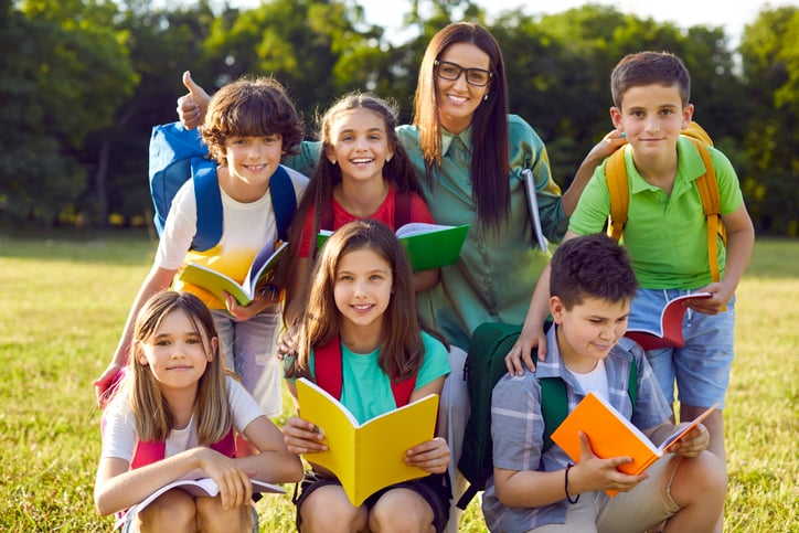 Group portrait of happy school children together with their teacher during fun class outside