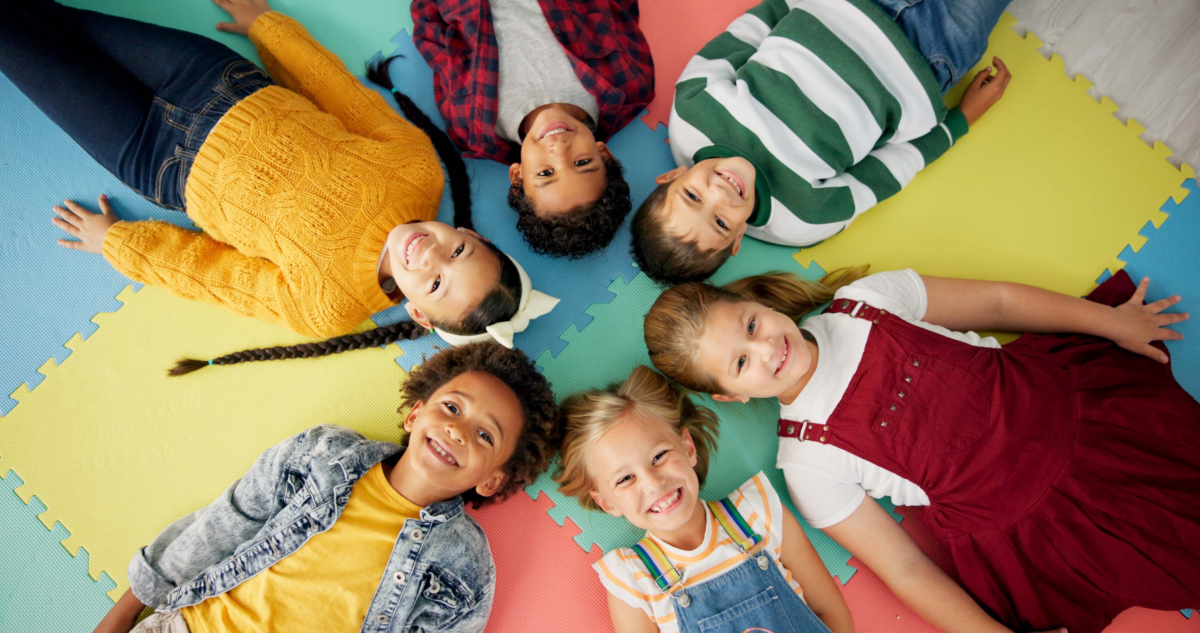 Group, kids and happy on floor for education, learning and knowledge with game for bonding