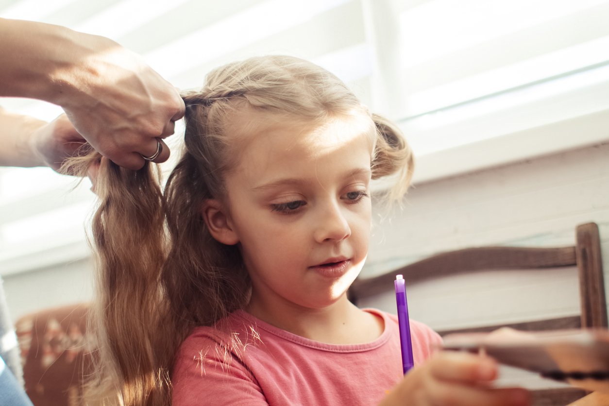 Mom is combing her daughters hair