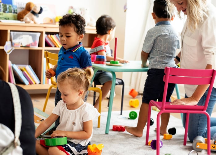 Nursery children playing with teacher in the classroom