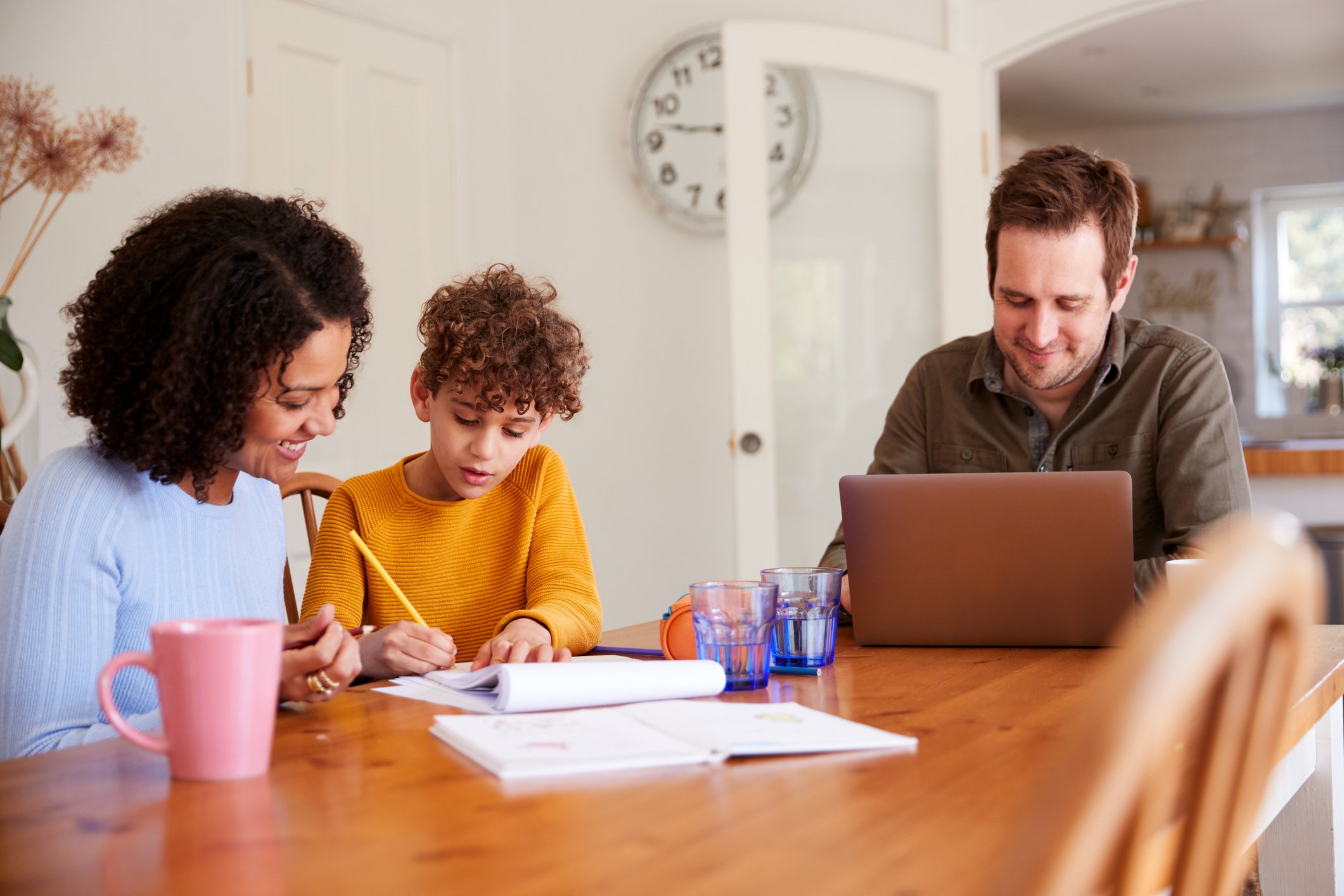 Parent guiding child through homeschool lesson at home desk