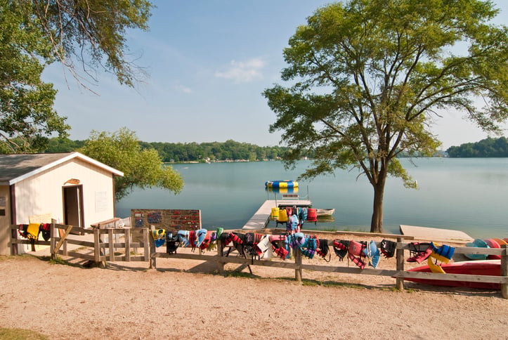 Summer Camp Lake with Life Jackets Hanging on Fence
