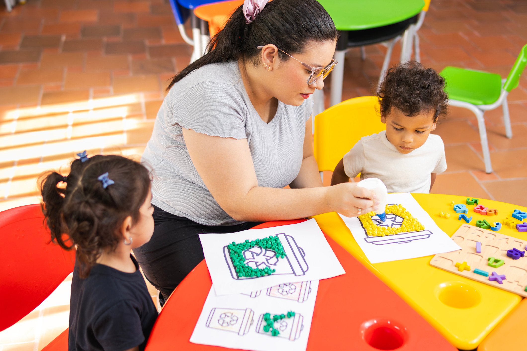 Teacher Helping Preschoolers with Craft Project