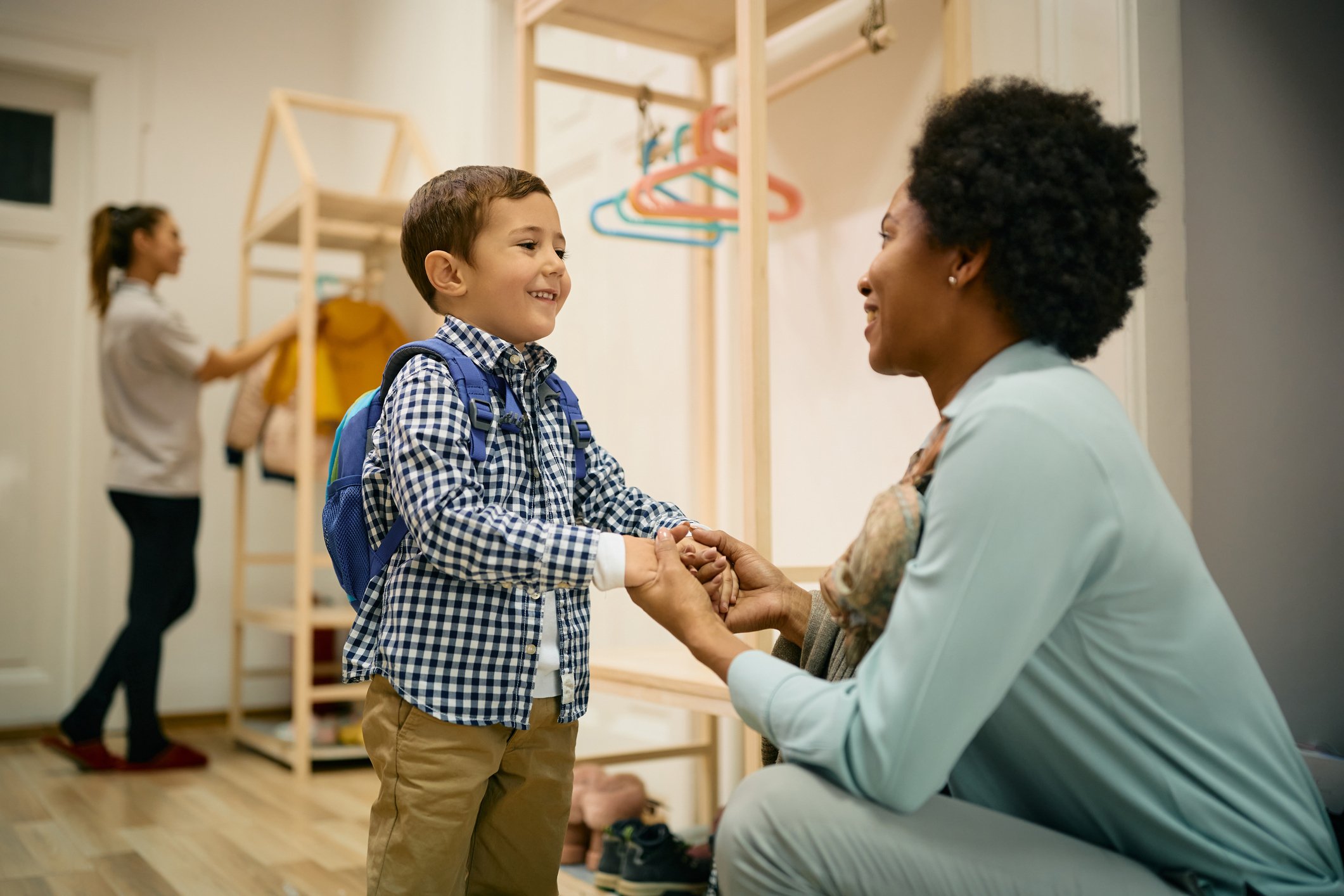 Parent holding hands with child during drop-off at a before school childcare center