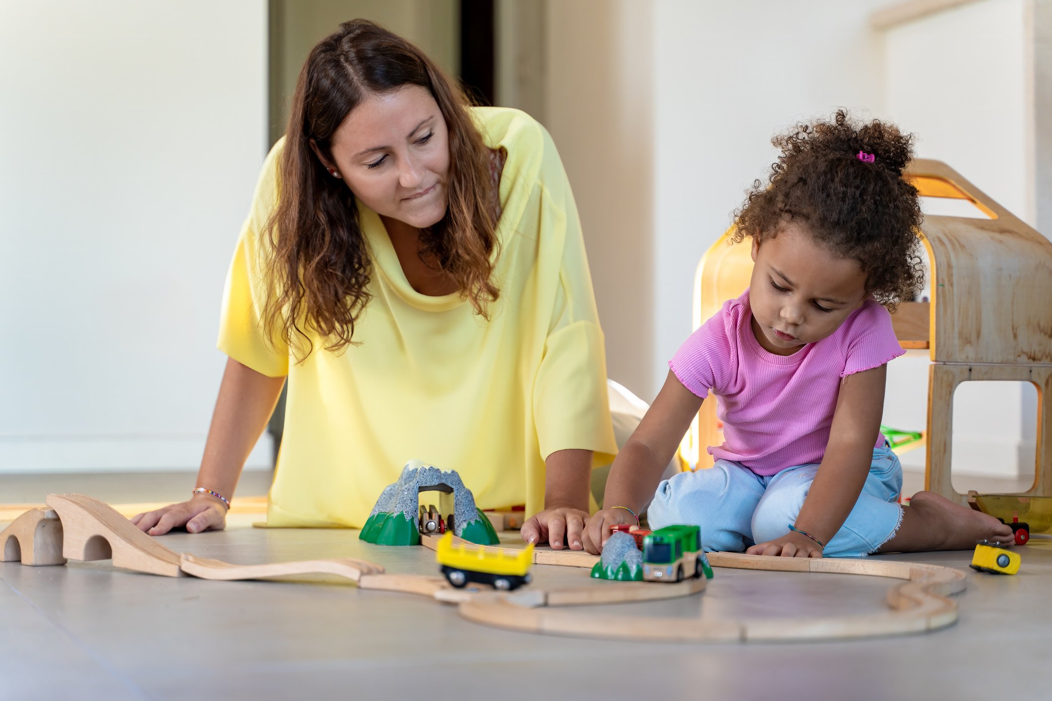 Caregiver guiding a young child in a CCDBG program during one-on-one playtime at a licensed childcare center