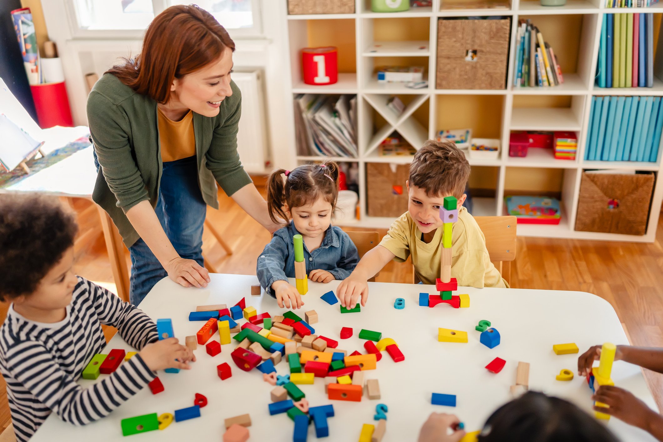 Children building with colorful blocks under teacher supervision in a high-quality childcare program supported by the Child Care and Development Block Grant